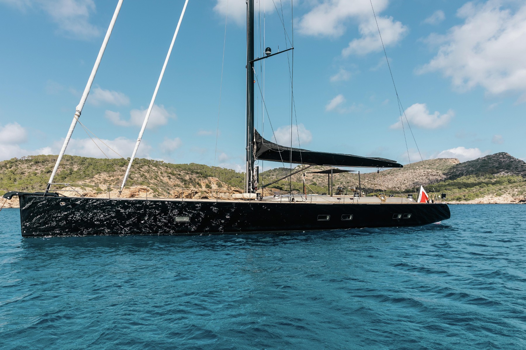 Custom black sailing yacht in crystal-clear Mediterranean waters