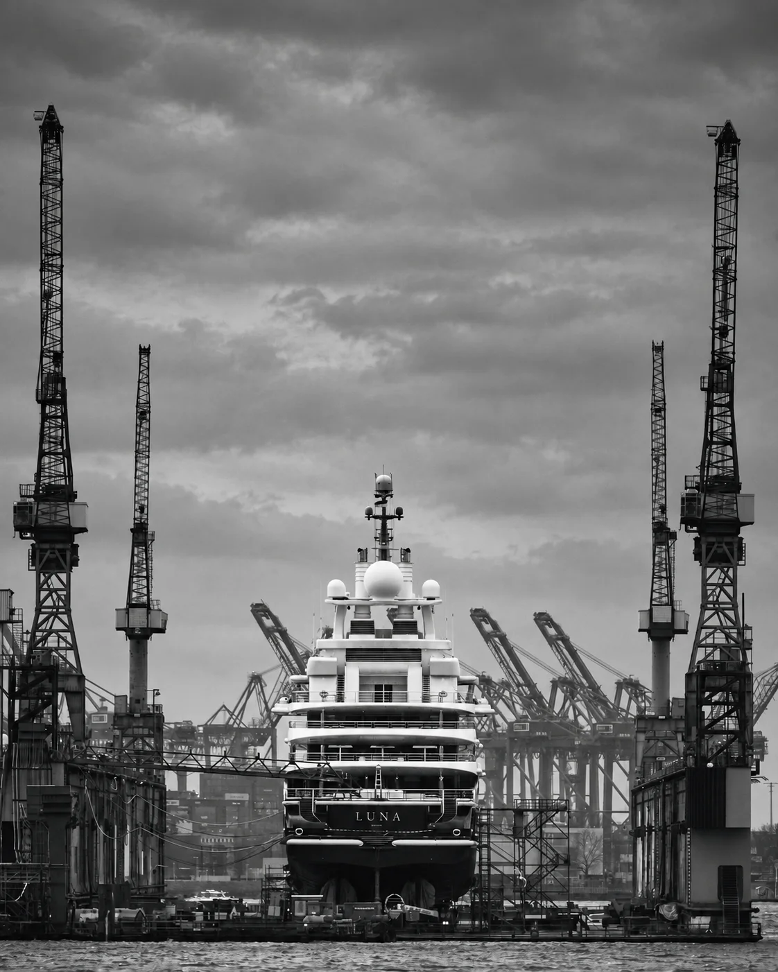 The superyacht Luna alongside an industrial dock.