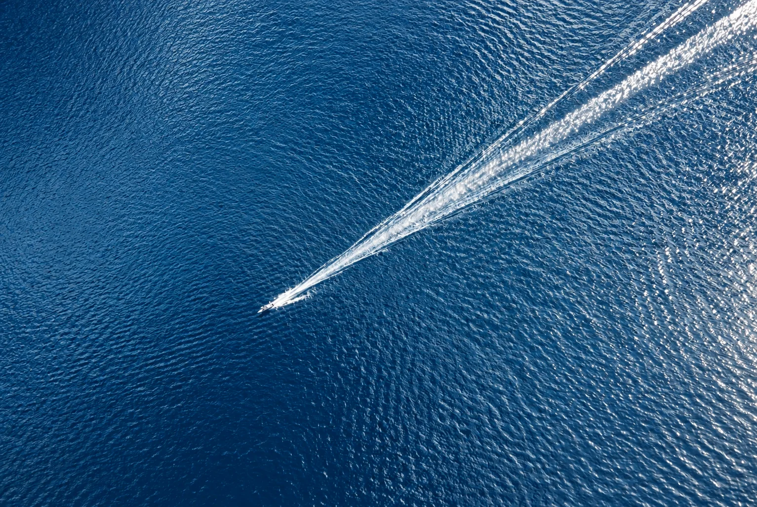 A boat leaving a long wake across calm water.