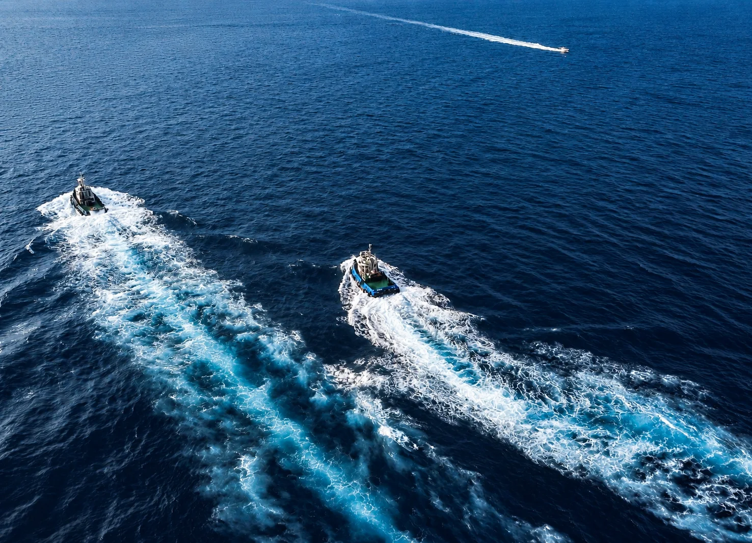 Intersecting boat wakes across a calm sea.