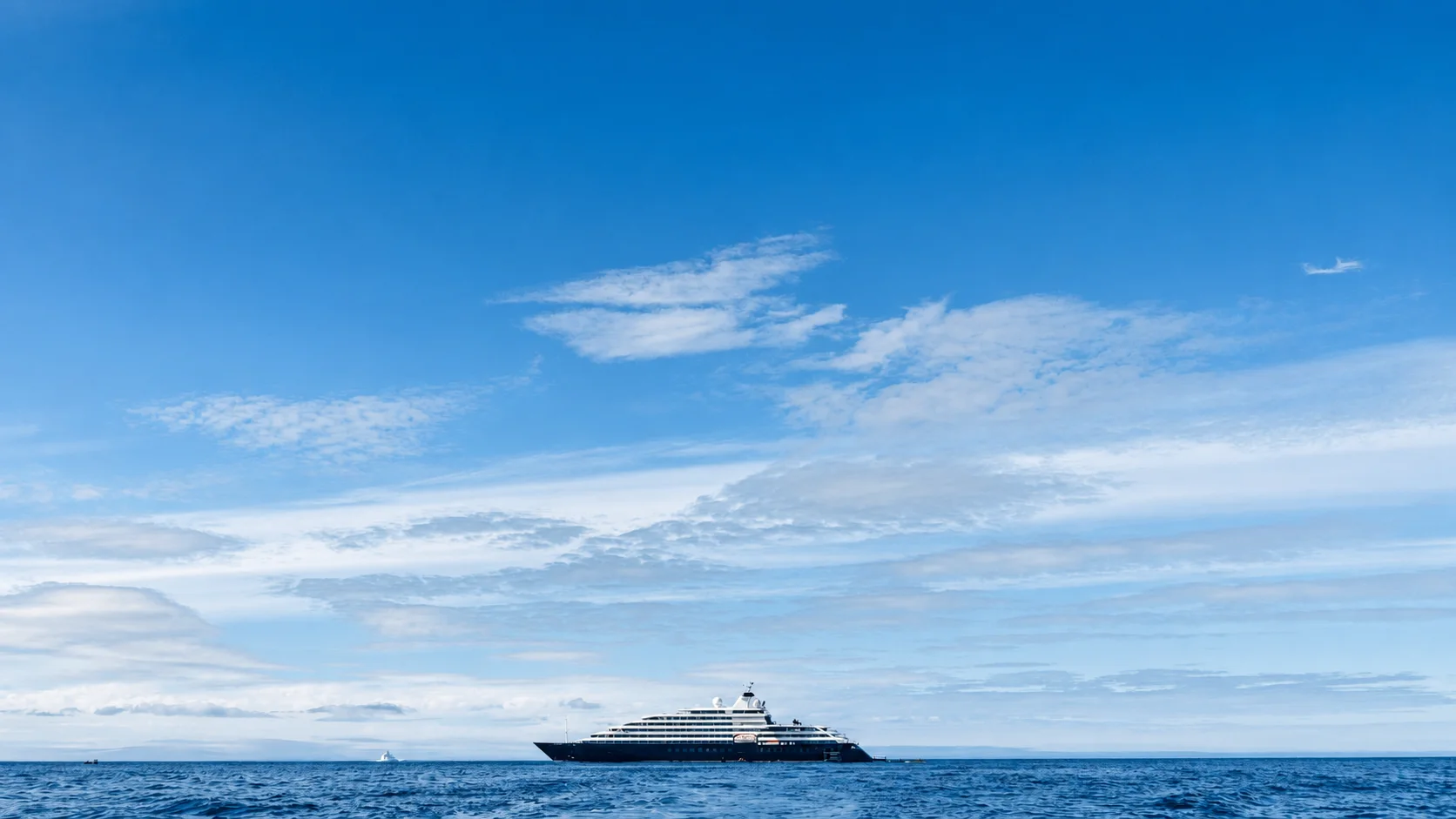 A yacht on the distant horizon in open water.