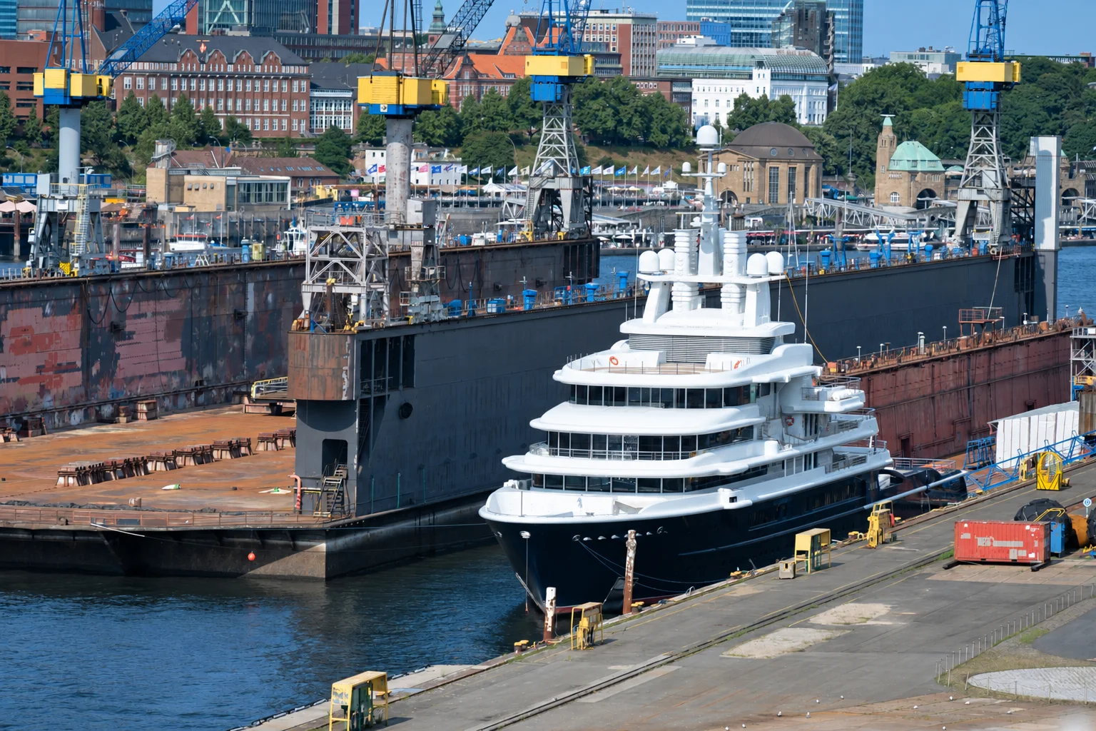 A superyacht berthed beside an industrial quay.