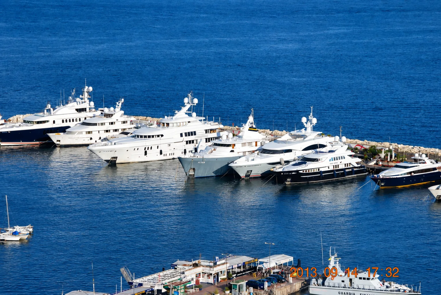 Superyachts moored along a stone breakwater.