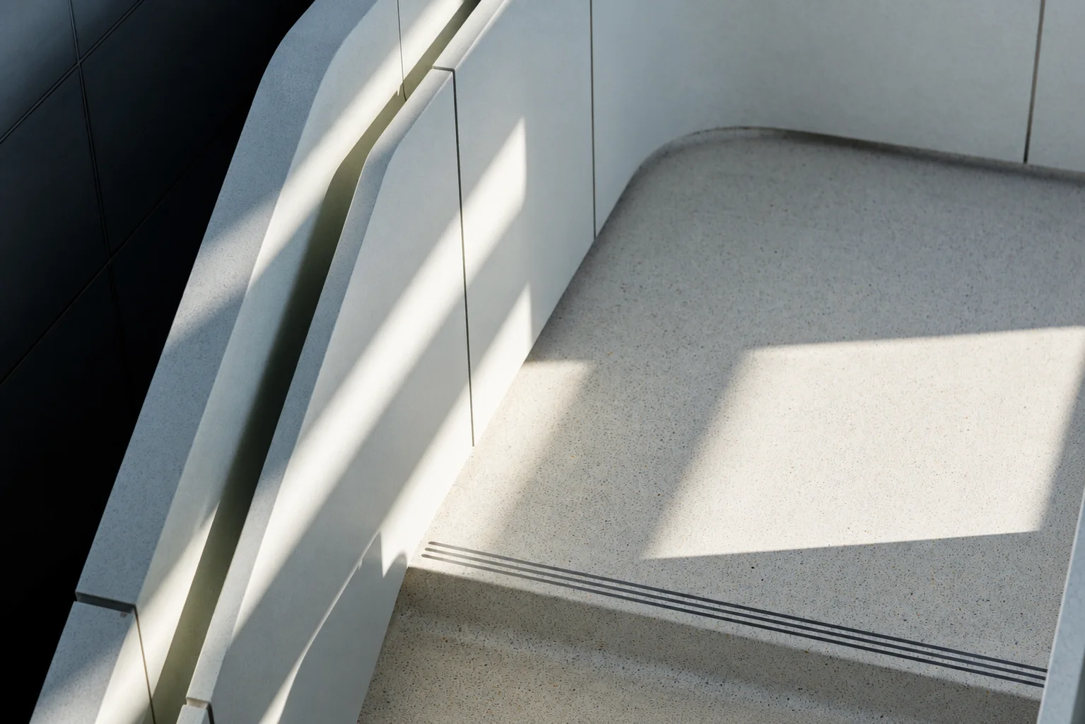 A minimalist staircase illuminated by natural sunlight.