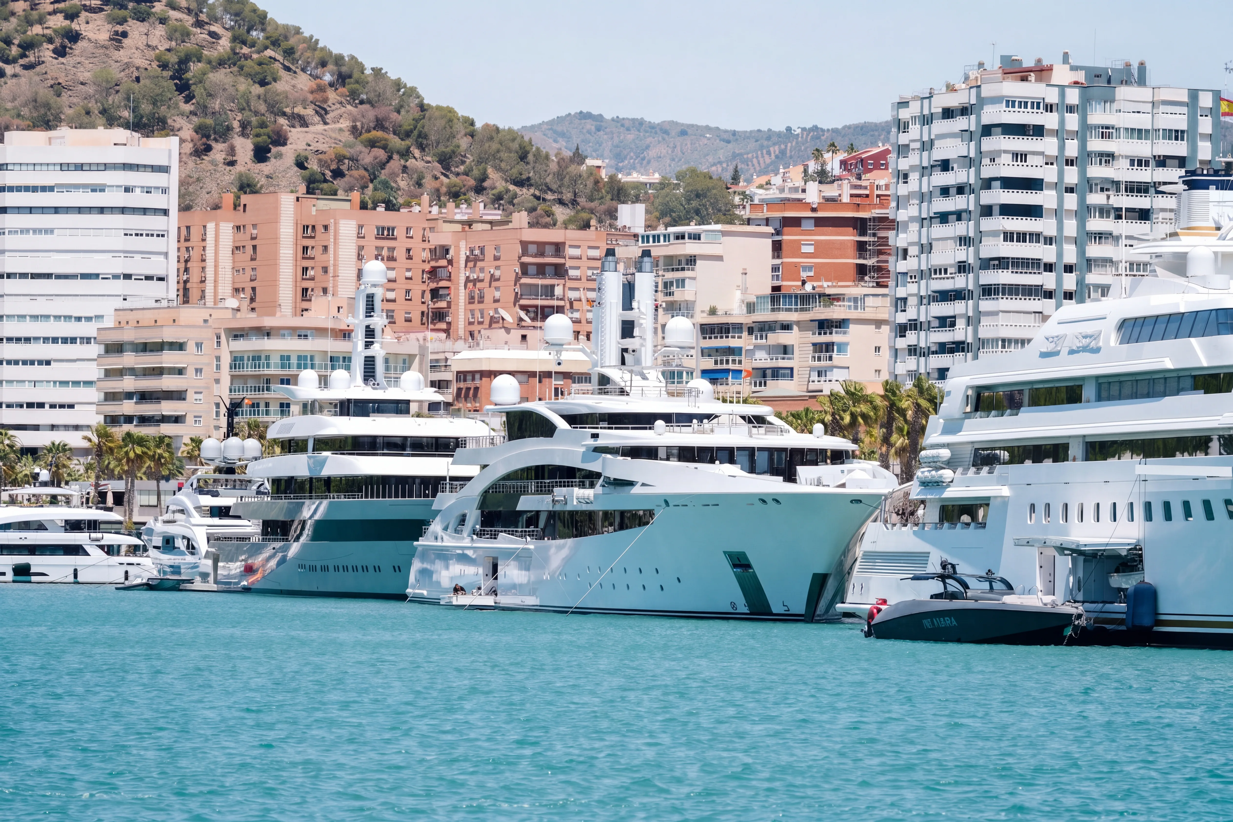 Motor yacht at anchor in a bay with a mountainous coastline behind