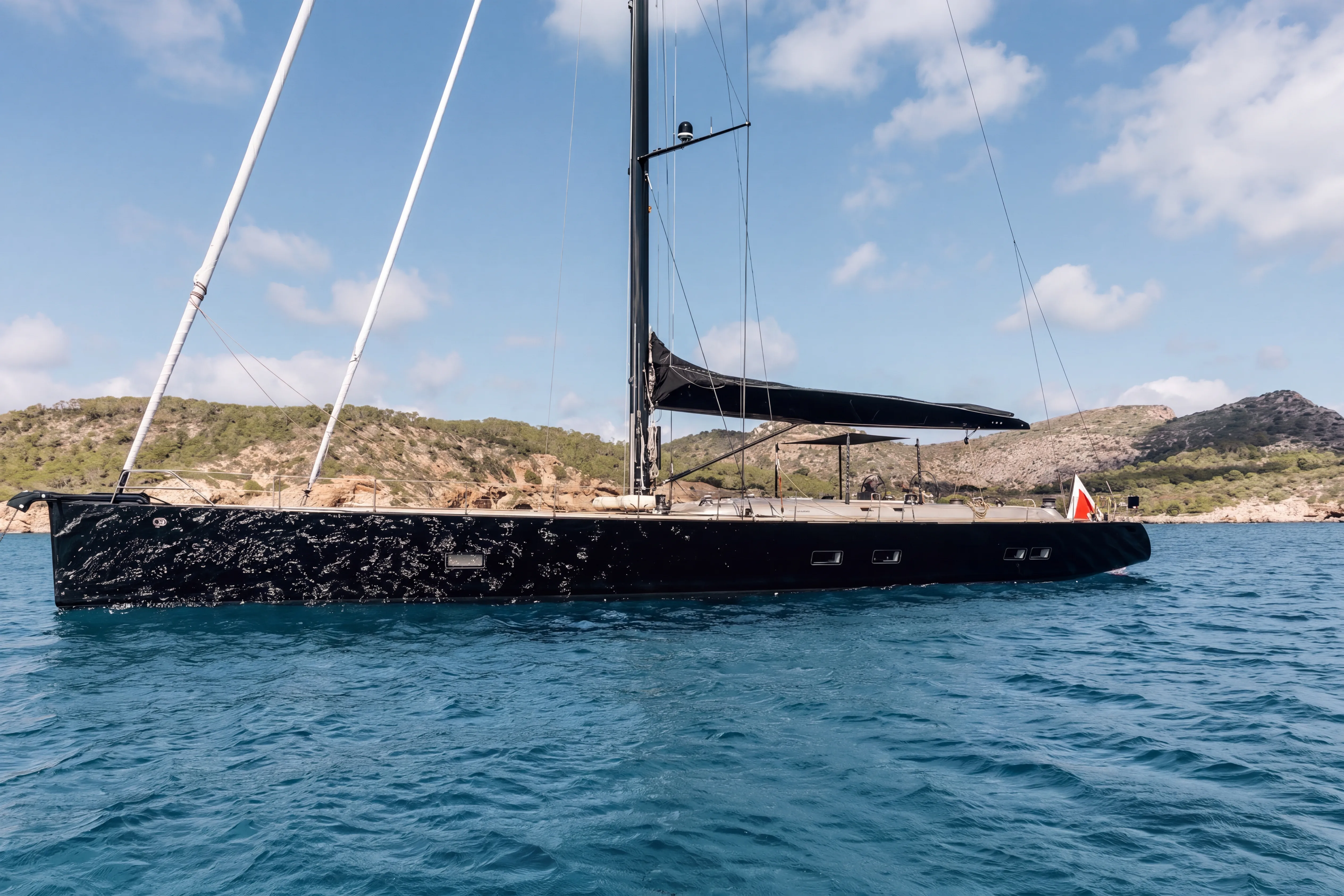 Individuelle schwarze Segelyacht im kristallklaren Wasser des Mittelmeers