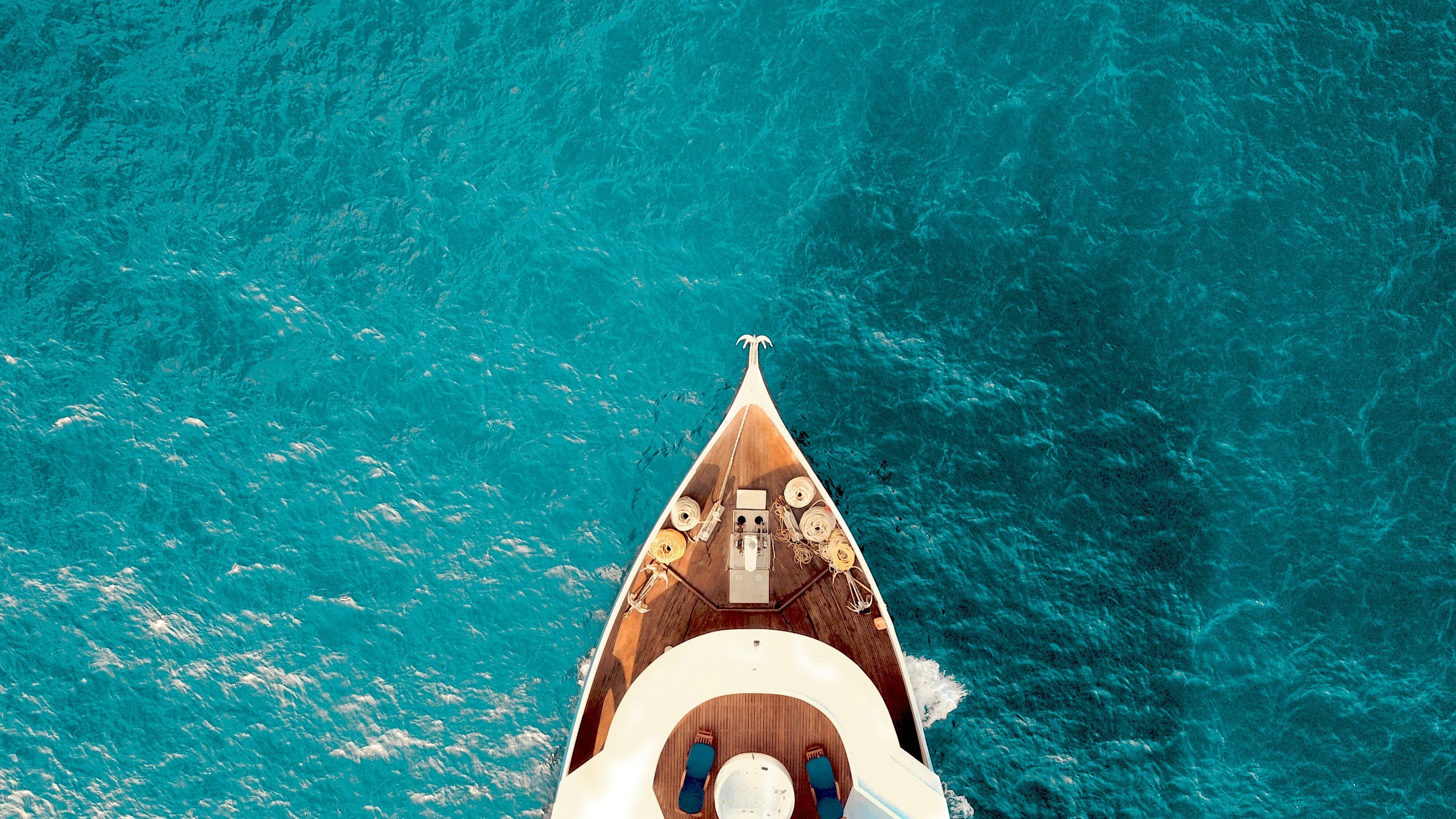 Yacht bow cutting through crystal-clear turquoise waters